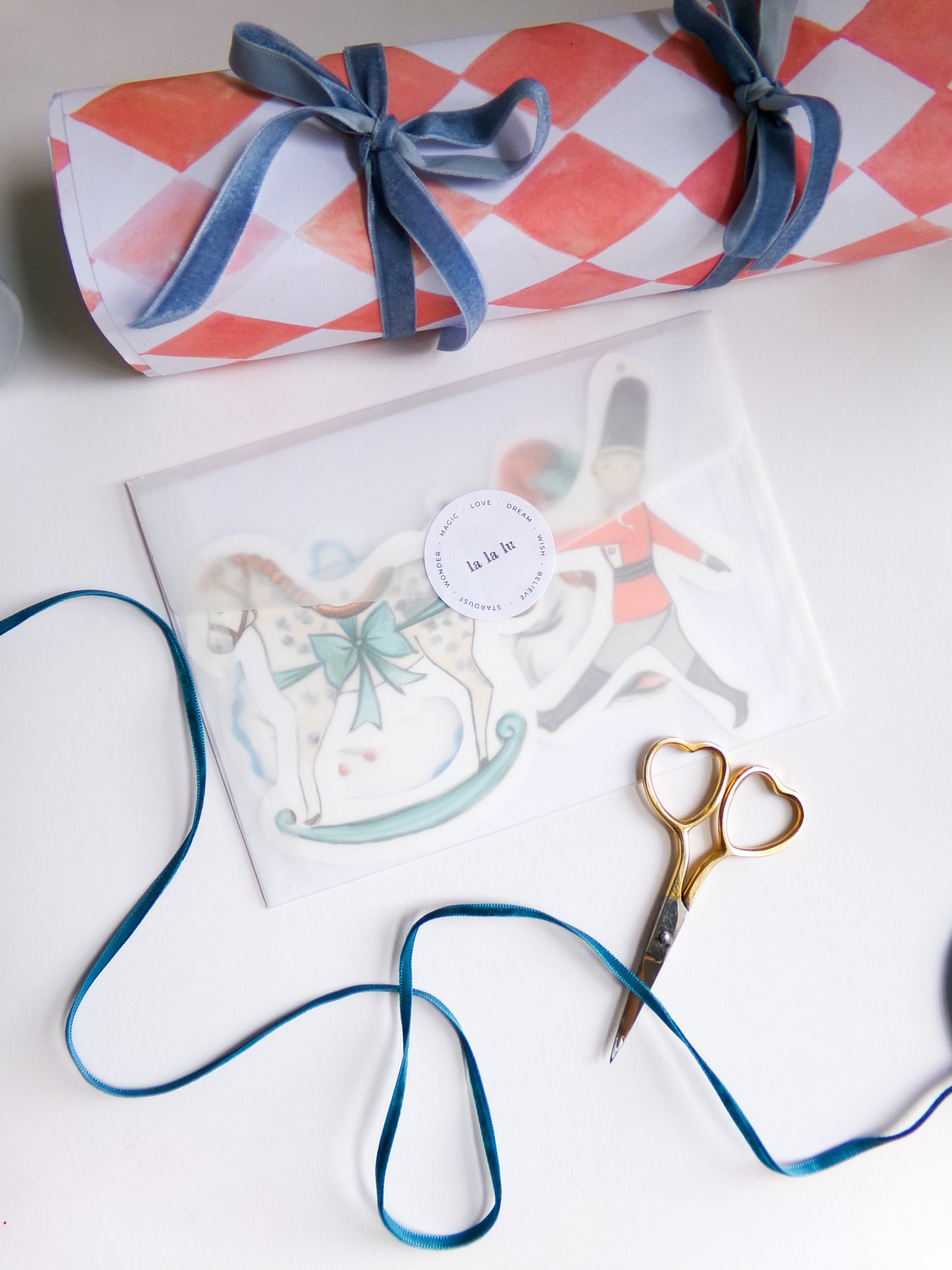 Gift wrap with a bow, scissors, and decorative card on a white surface