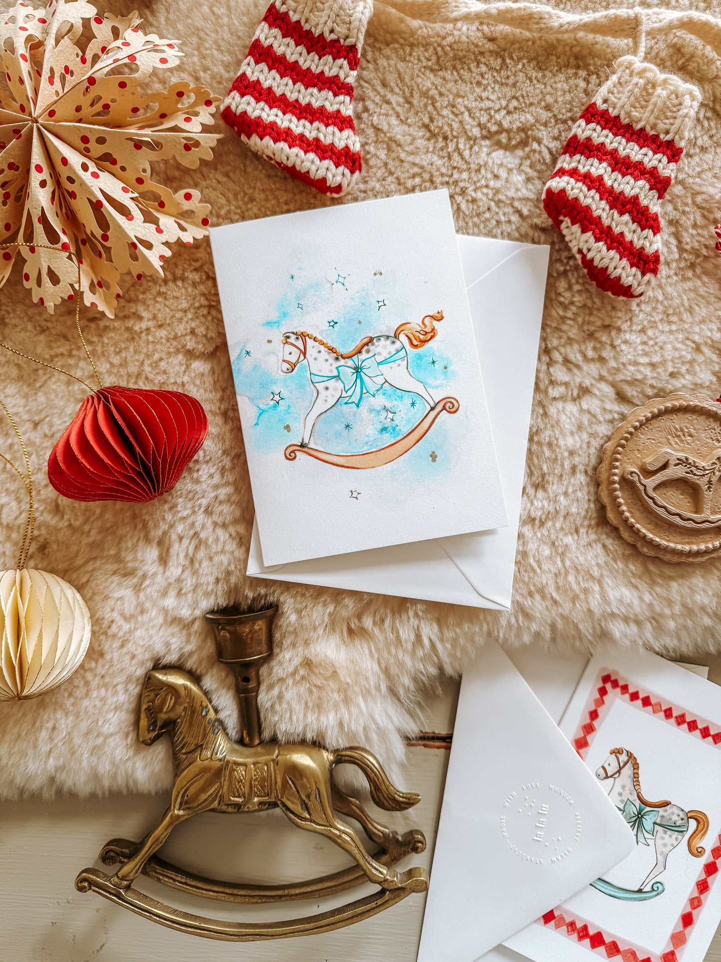 Christmas card with a rocking horse design on a decorative surface with ornaments.