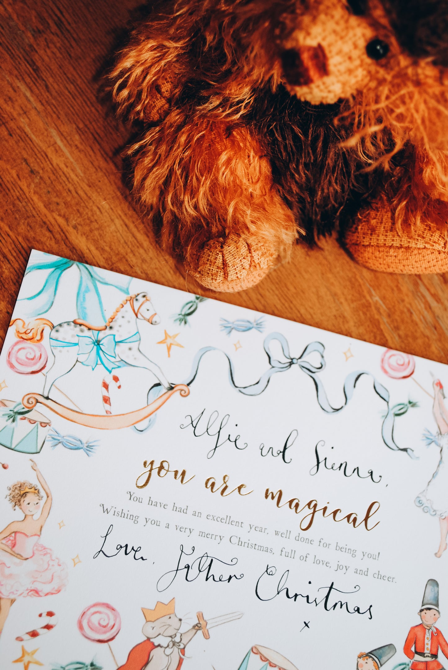 Stuffed lion toy next to a Christmas card with decorative elements on a wooden surface