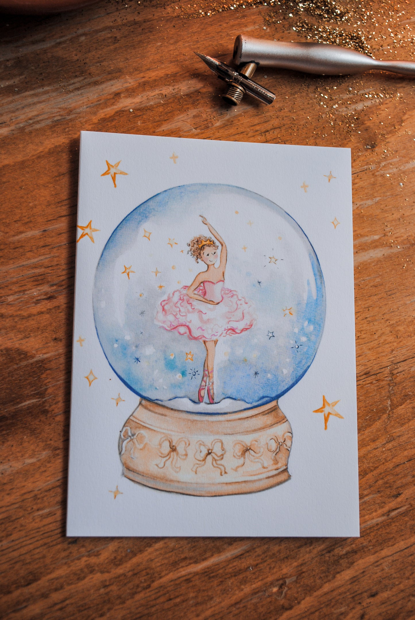 Illustration of a ballerina in a snow globe on a wooden surface with tools.