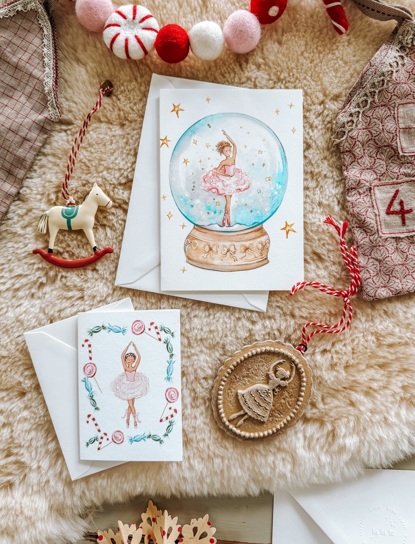 Christmas-themed greeting cards with a snow globe design on a soft surface with decorative items.