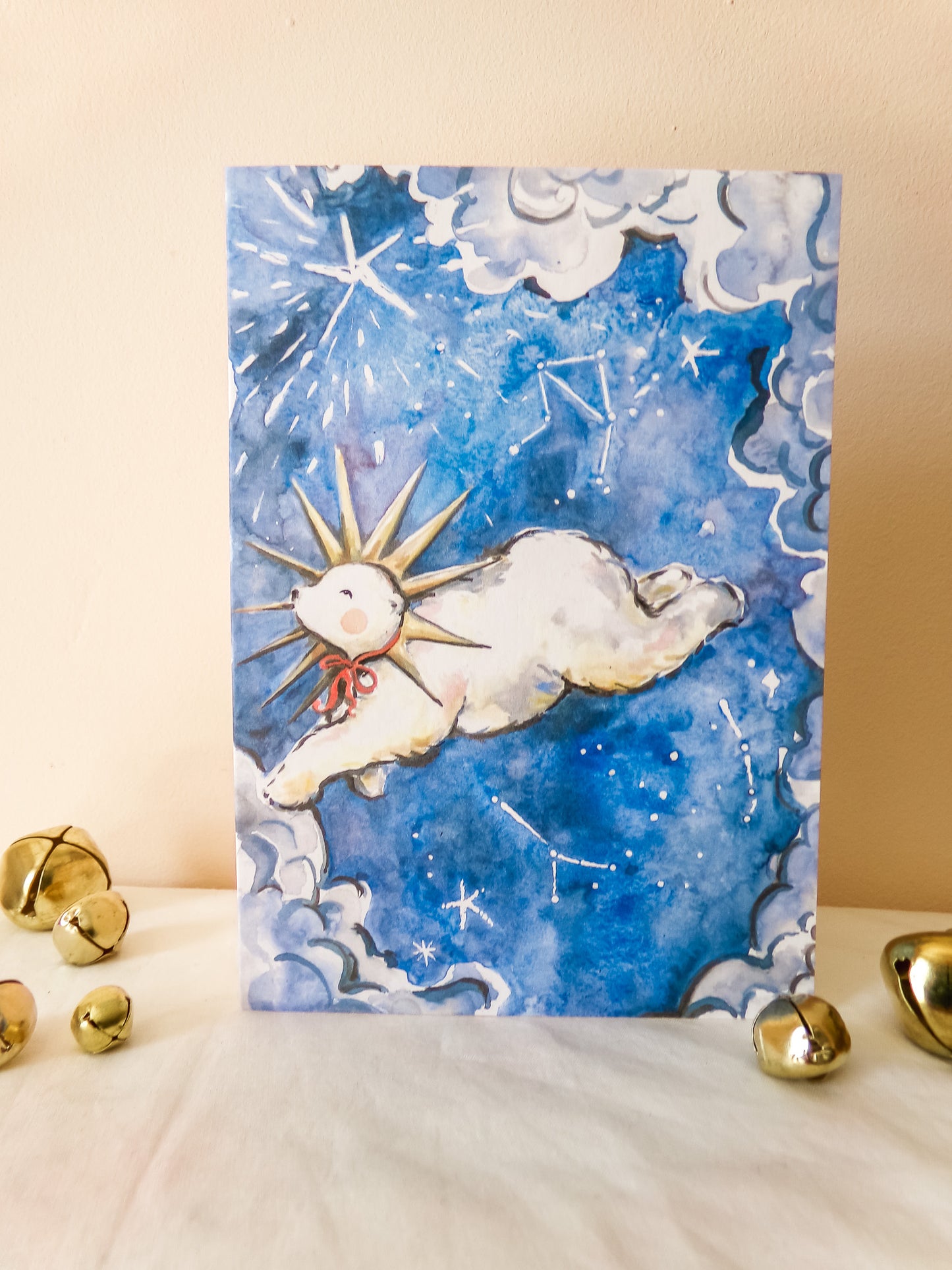Card with a cartoon dog lying on a cloud under a starry sky, surrounded by gold bell decorations.