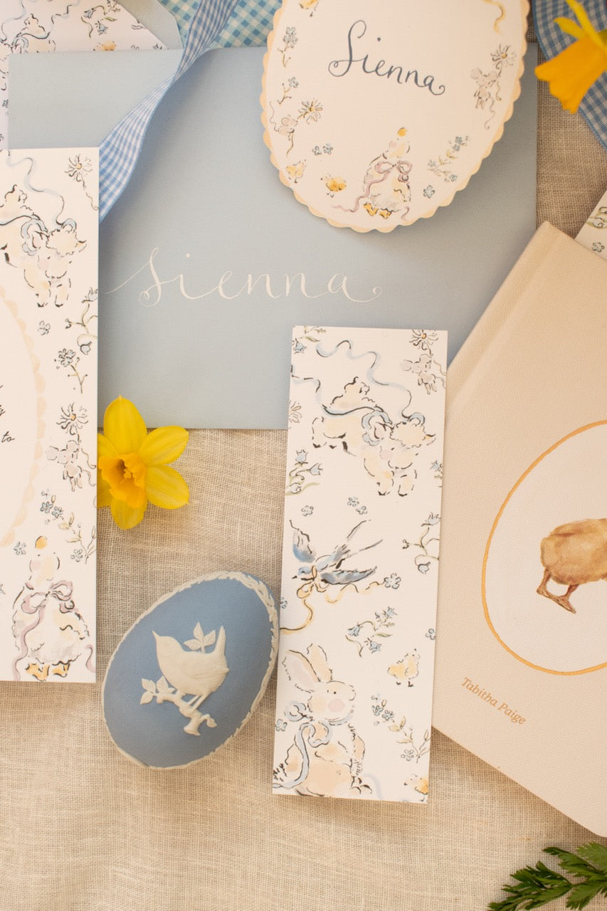 Collection of decorative items including cards, a bookmark, and a small round object with a bird design on a textured surface.