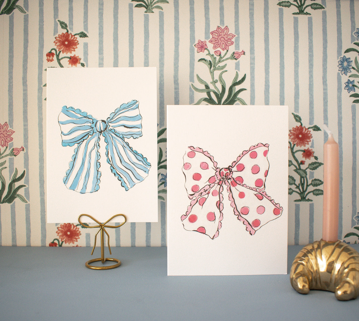Two prints of bows on a decorative wall with floral elements.
