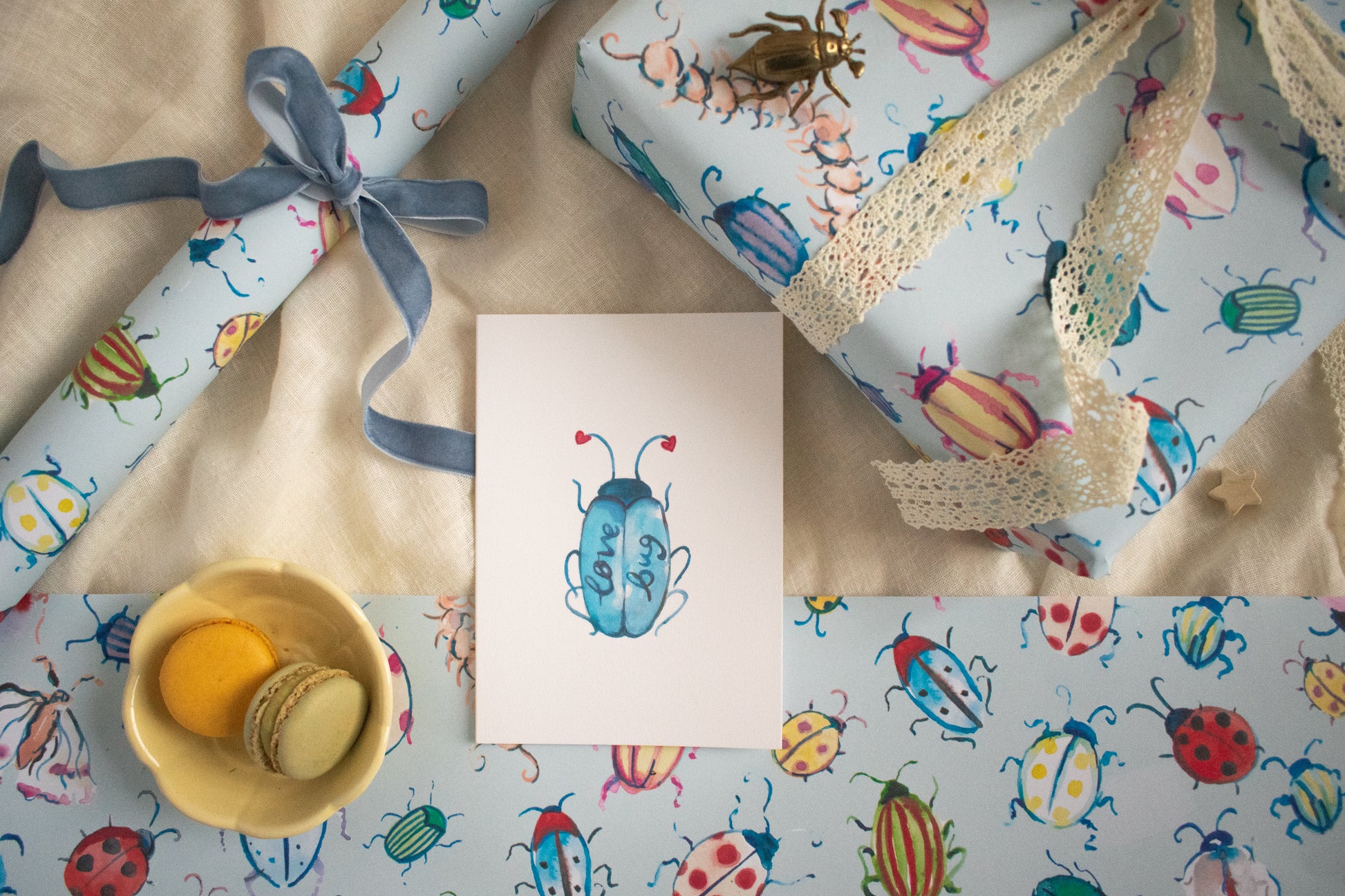 Gift wrap with colorful beetle design, a card, and a small bowl on a matching background.