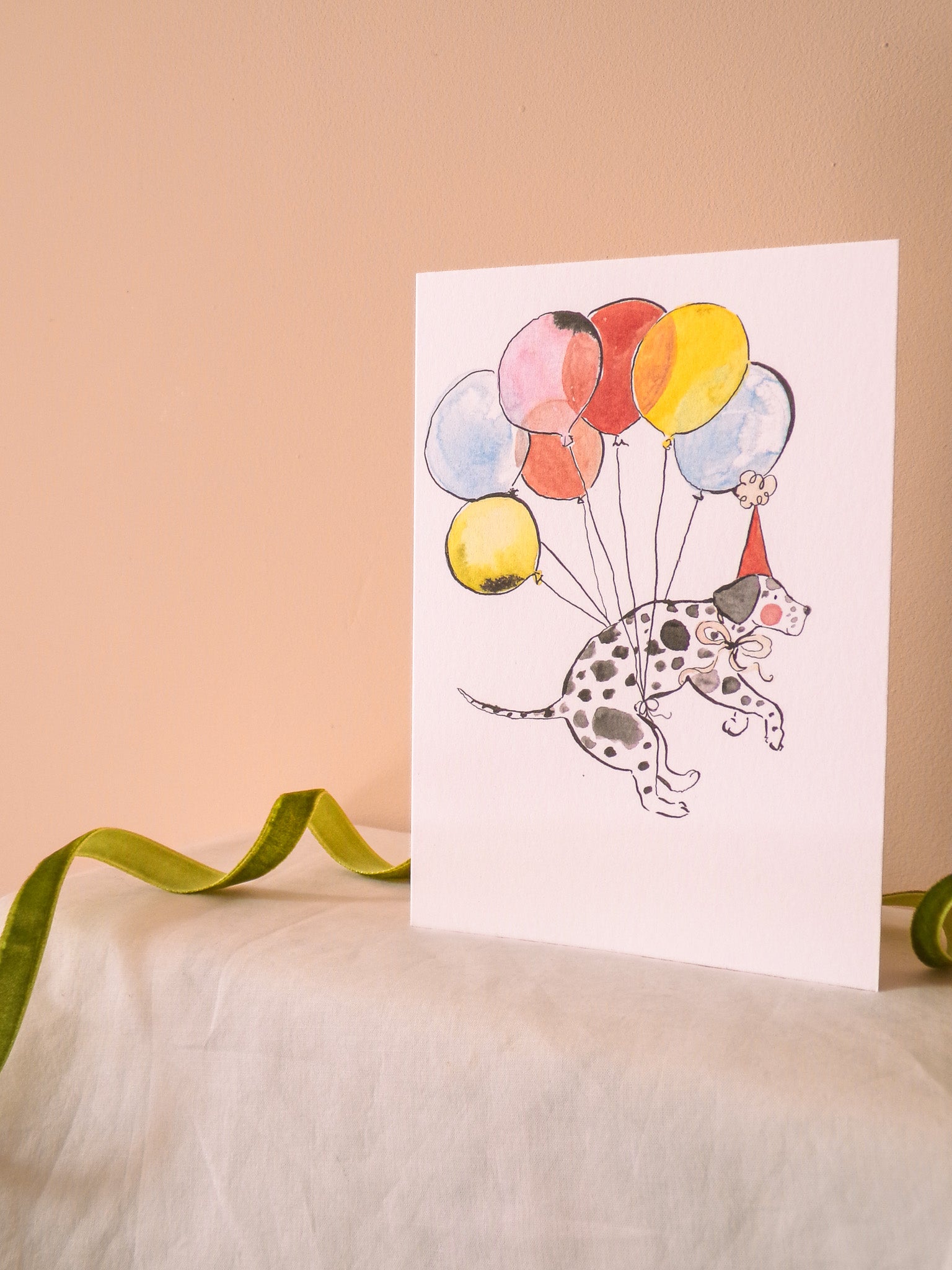 Card with a Dalmatian dog holding balloons on a beige background