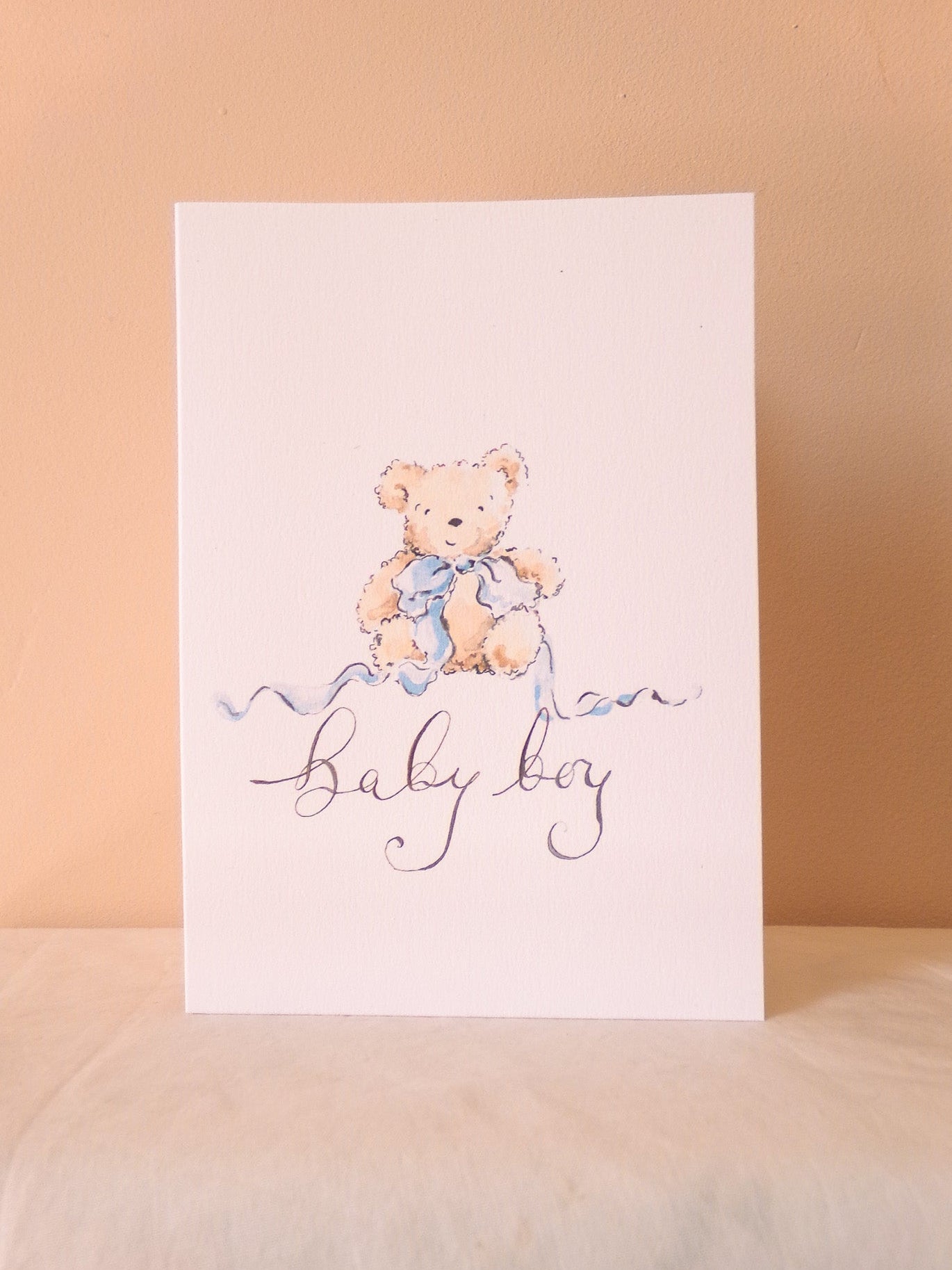 Greeting card with teddy bear illustration and 'Baby Boy' text on a beige background