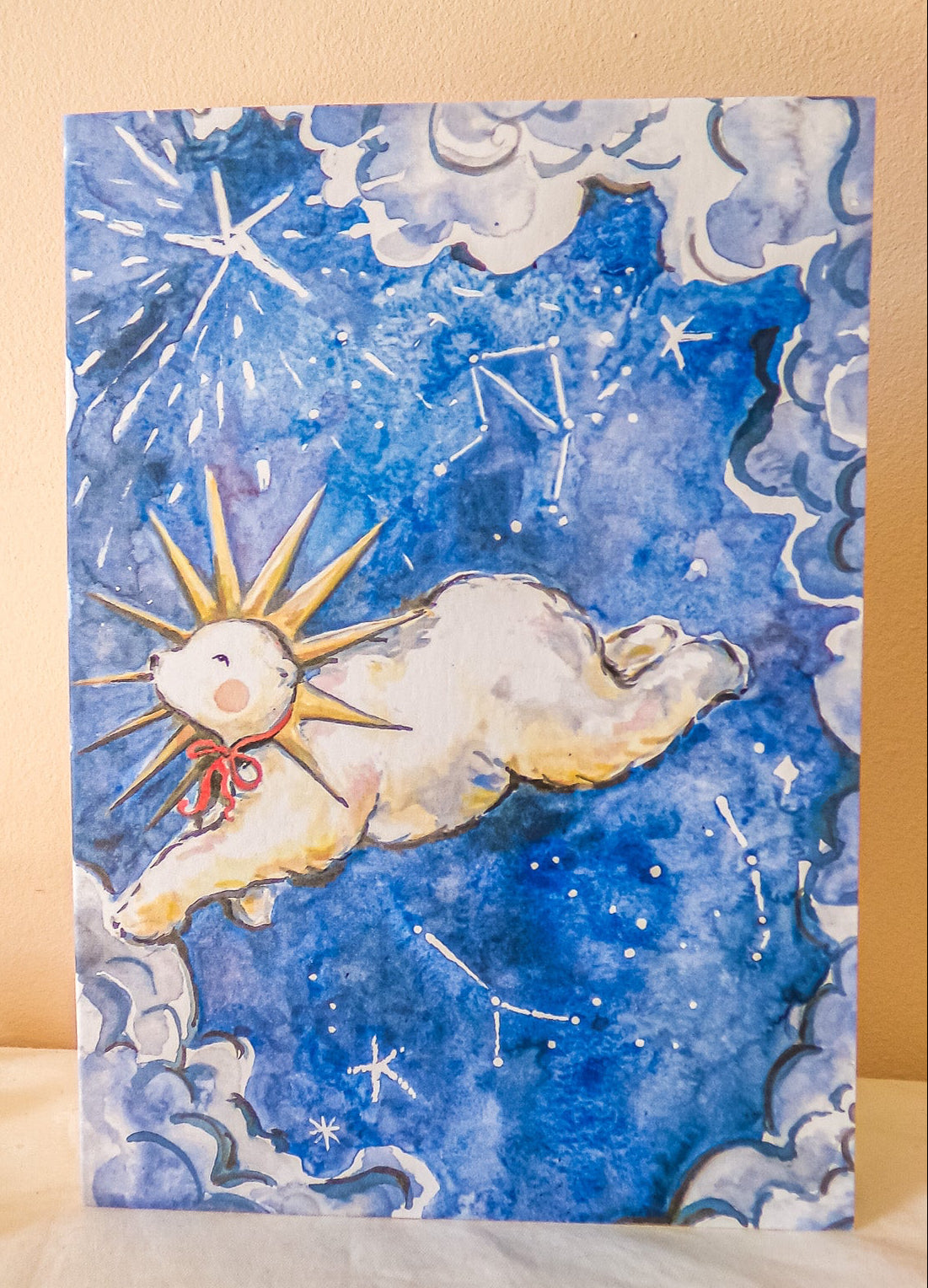 Notebook with a celestial design featuring a sun and moon, placed on a light surface with gold jingle bells.