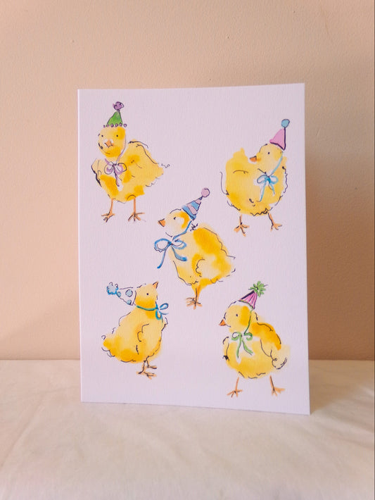 Card with illustrations of yellow chicks wearing party hats on a beige background