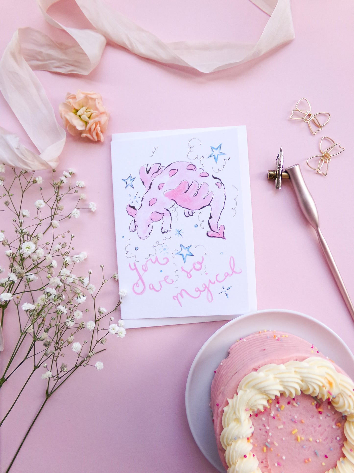 Card with a pink elephant and text 'You are so magical' on a pink background with flowers and a cake.