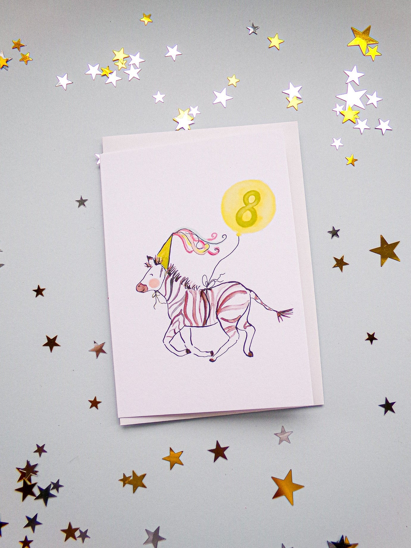 Greeting card with a unicorn design and number 8 on a gray background with star confetti.