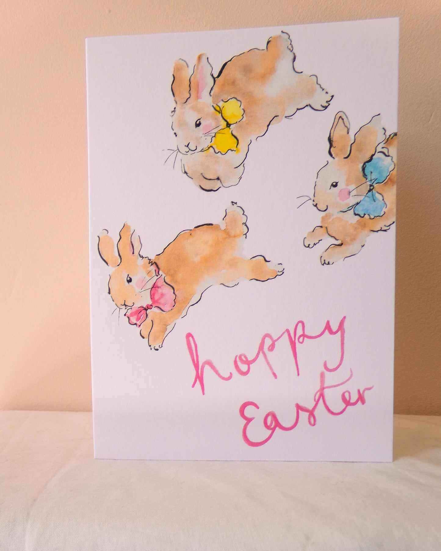 Card with Easter bunnies and 'Happy Easter' text on a beige background