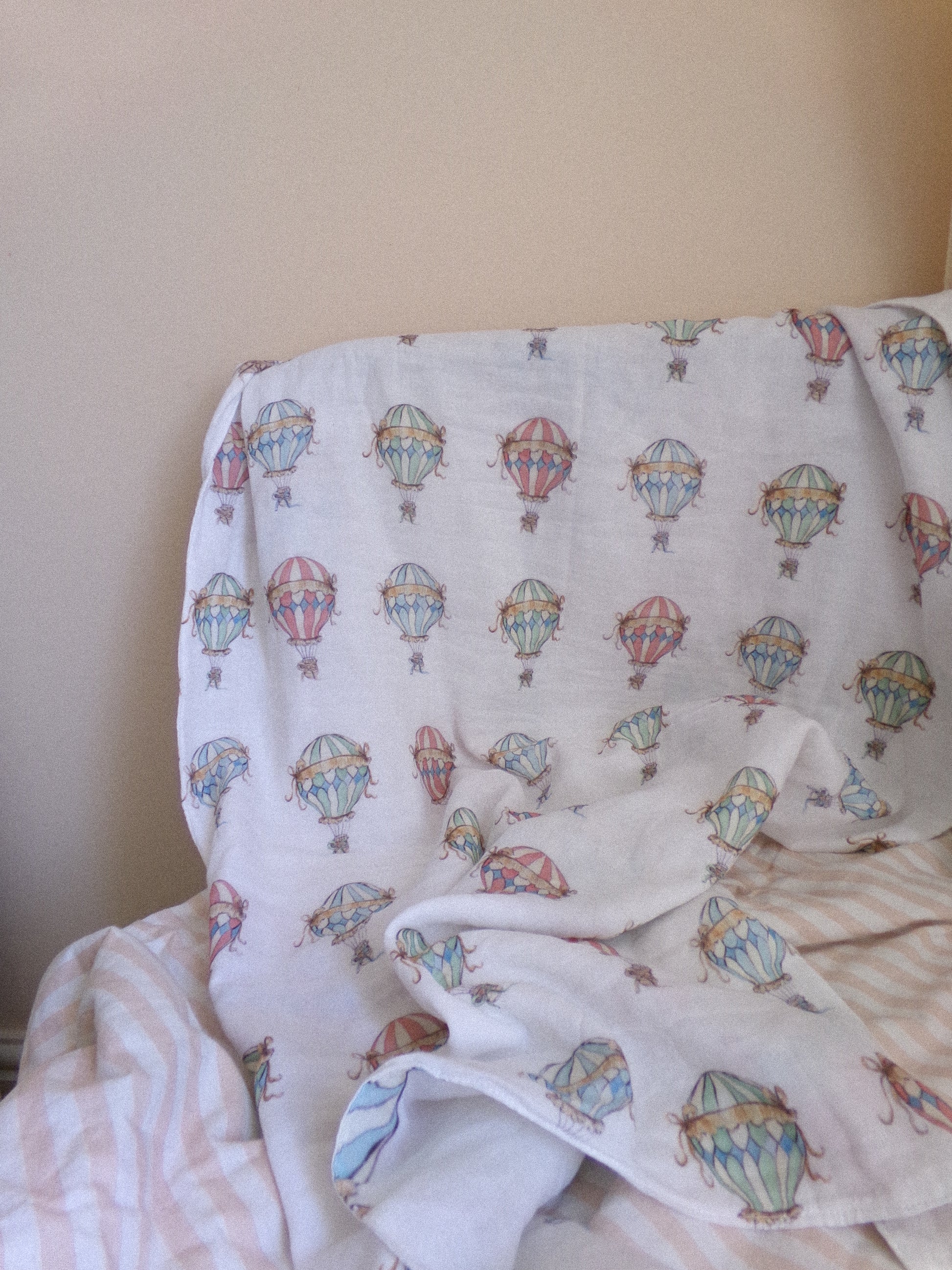 White blanket with colorful hot air balloon pattern draped over a chair.