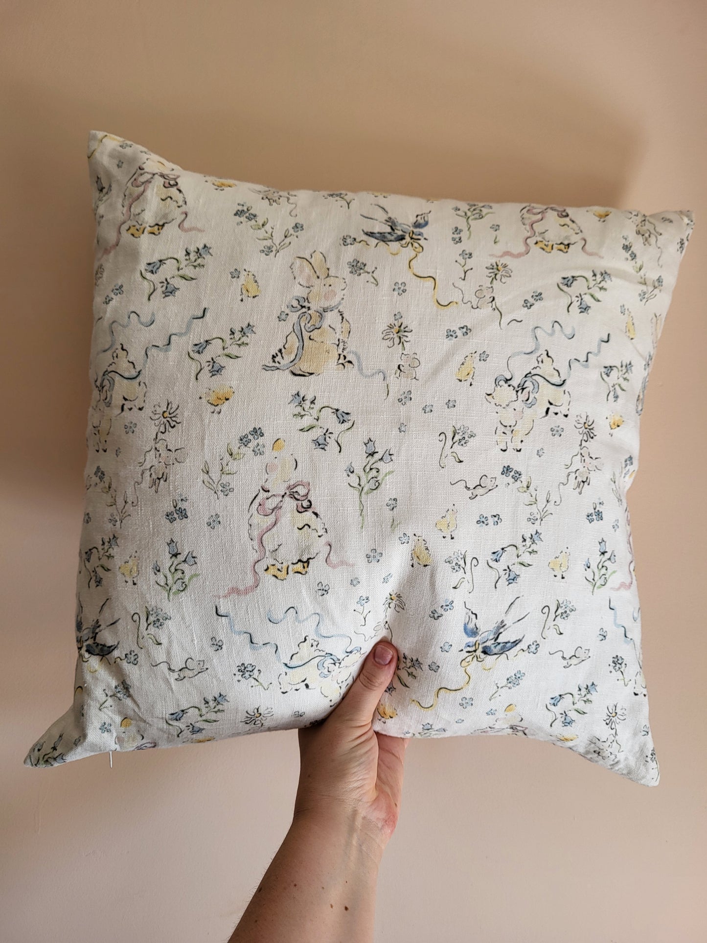 Hand holding a decorative pillow with animal print against a beige background