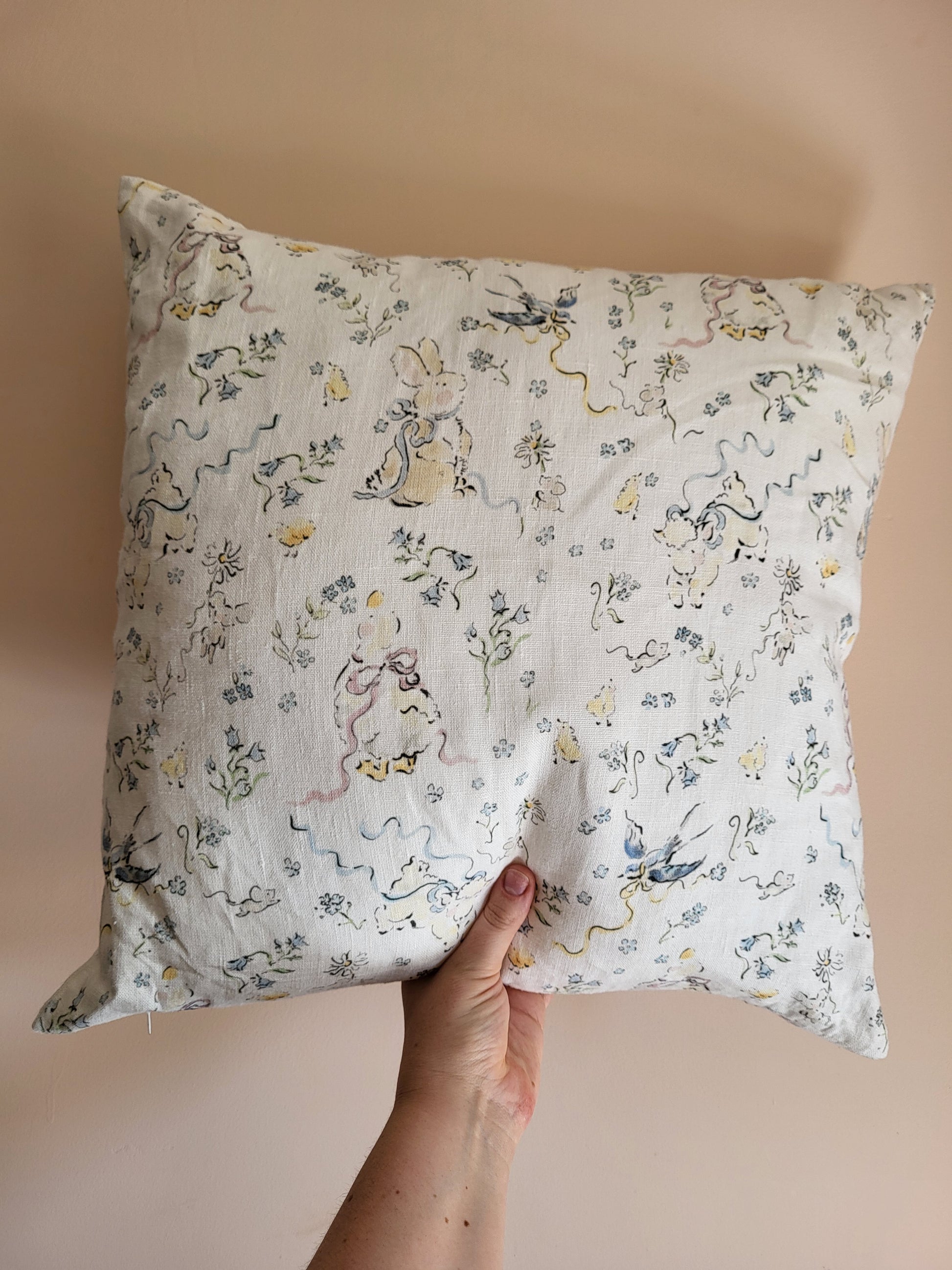 Hand holding a decorative pillow with animal print against a beige background
