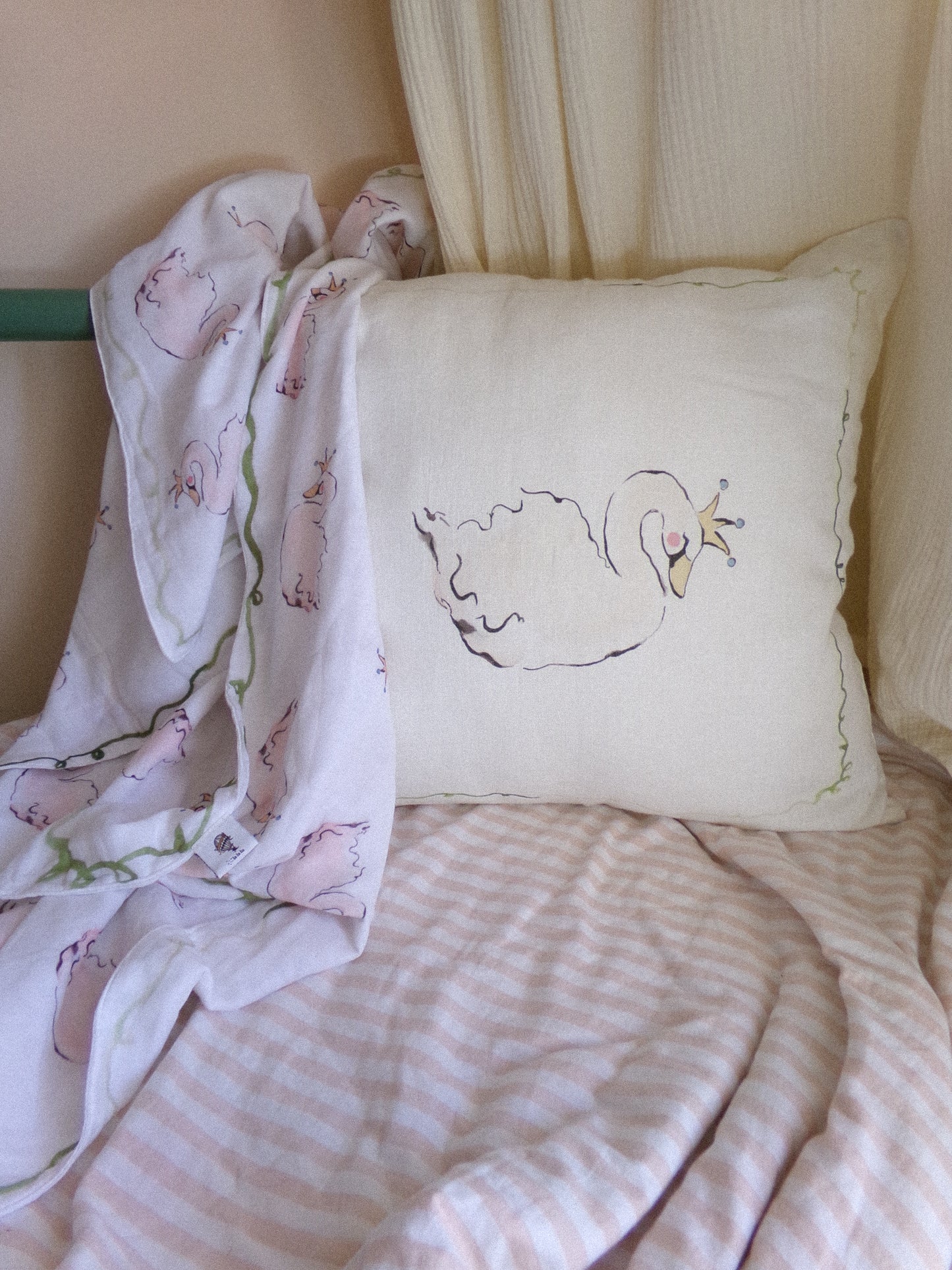 Decorative pillow with a swan design on a bed with striped bedding.