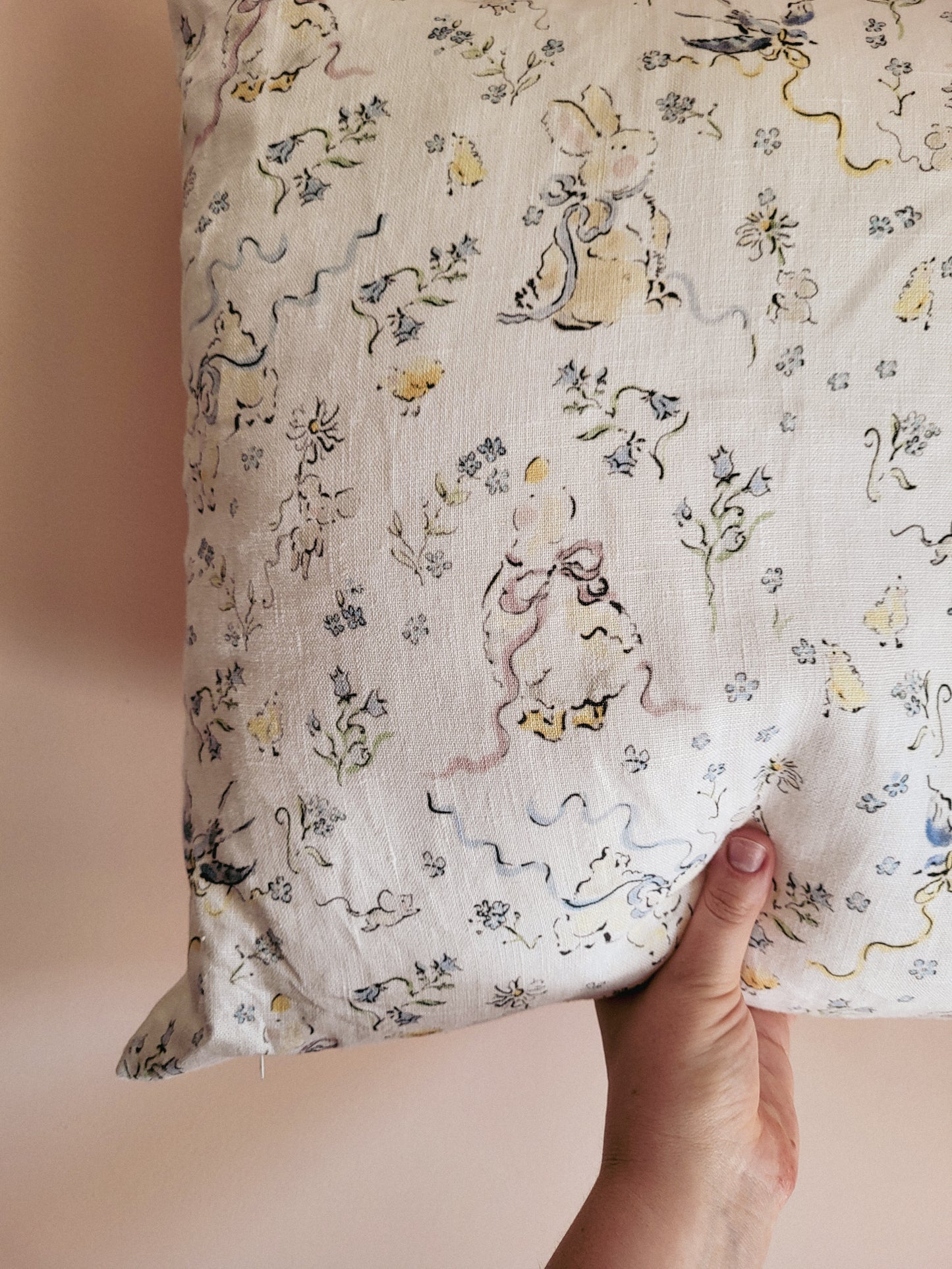 Floral-patterned fabric held by a hand on a beige background