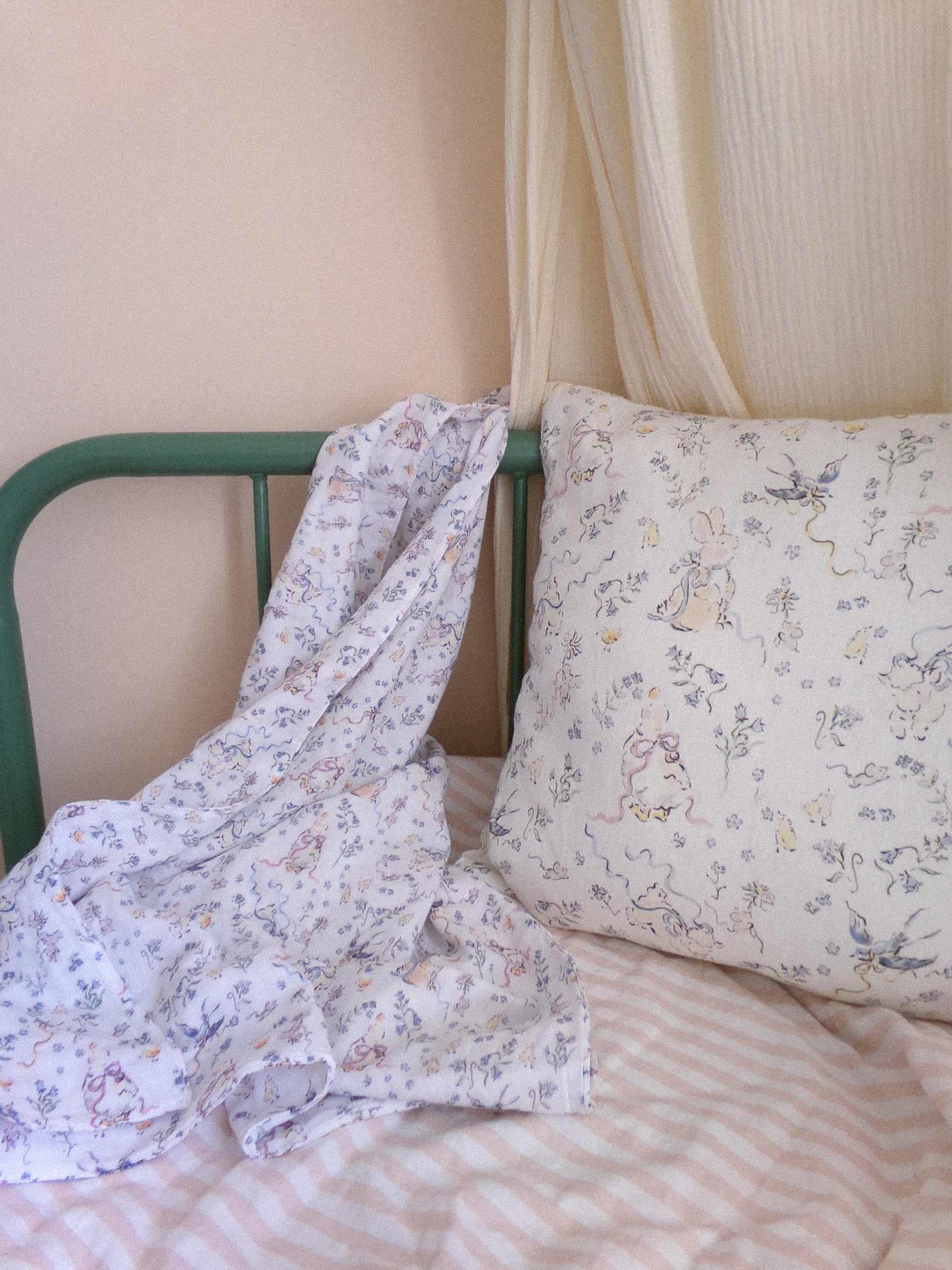 Floral-patterned pillow and blanket on a bed with a green headboard.