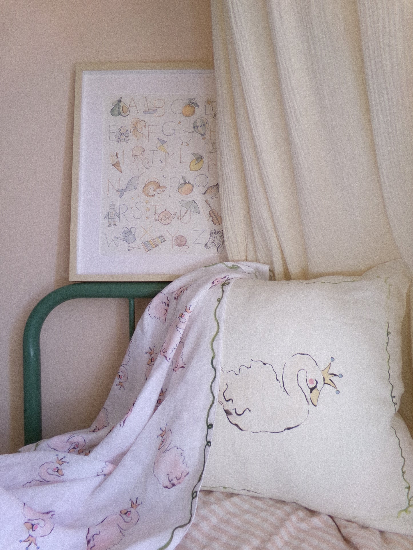Children's room with a green chair, embroidered pillow, and framed alphabet chart on the wall.