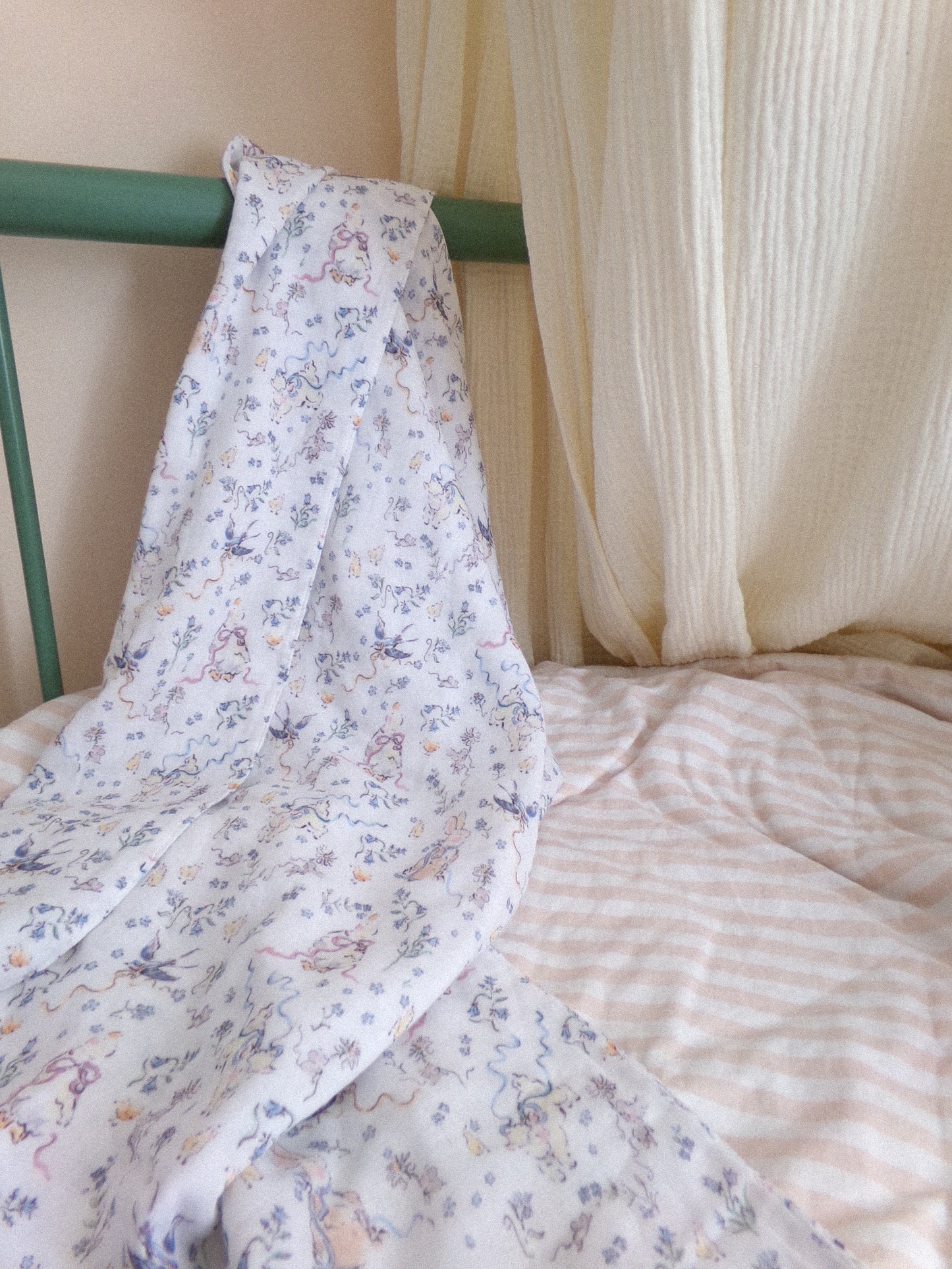 Floral-patterned blanket draped over a bed with a green headboard and striped bedding.
