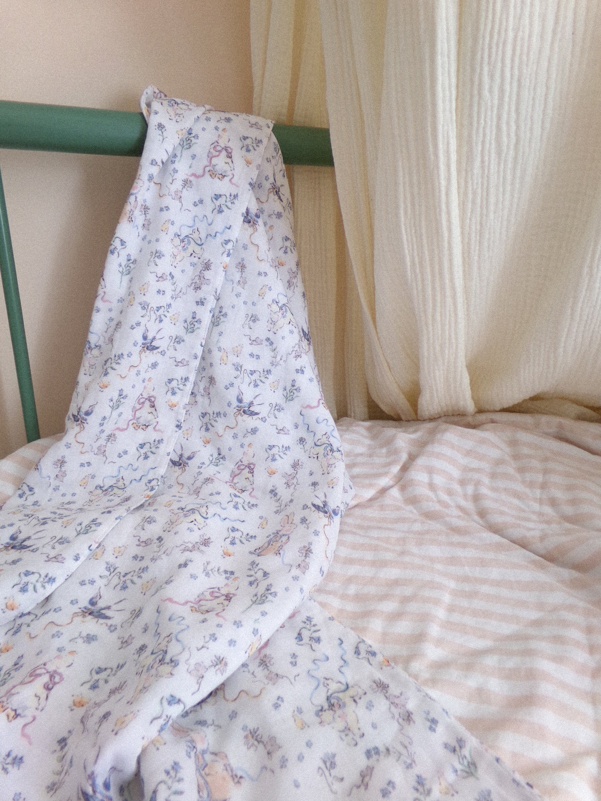 Floral-patterned blanket draped over a bed with a green headboard and striped bedding.