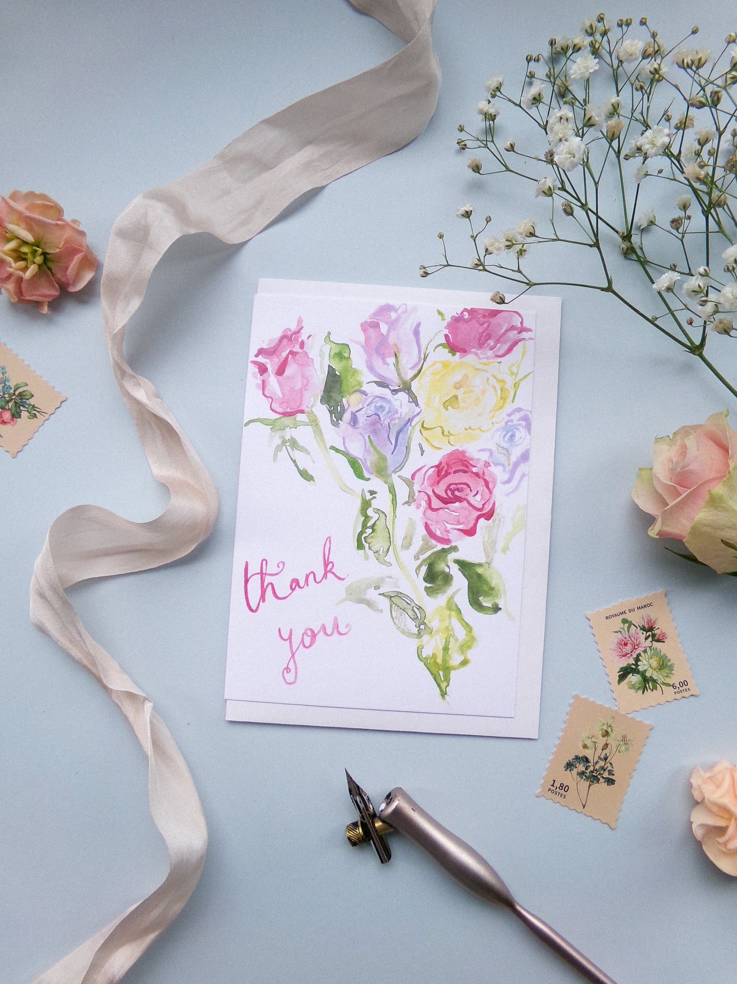 Floral card with 'thank you' text on a light blue background with flowers and ribbon.